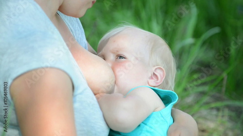 Young mother breastfeeding a baby in nature
