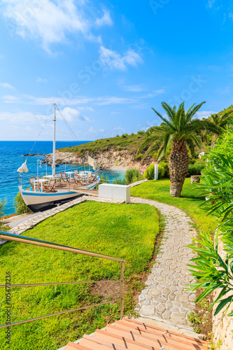 Path to traditional sailing boat in green area of Proteas bay on coast of Samos island, Greece