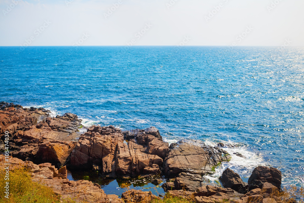 Black Sea coast in a hot summer day. Rocky coast with bright blue sea water and large stones.