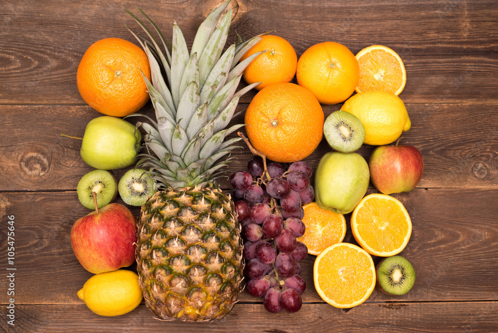 Tasty fruit background with orange, kiwi, grape, apples and lemon on the wooden table Tasty fruit background with orange, kiwi, grape, apples and lemon on the wooden table