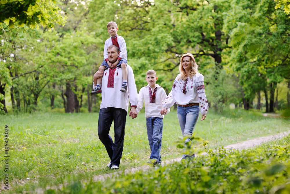 Obraz premium family in Ukrainian embroidered shirts are on a path in a forest