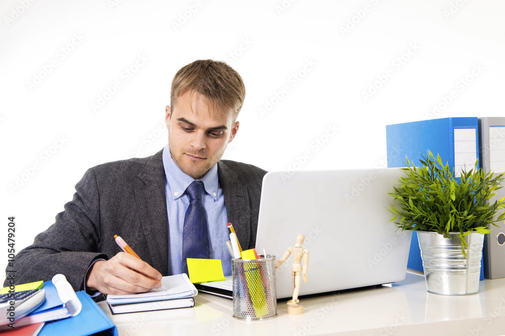 attractive businessman working busy with laptop computer writing on pad with pen at office desk attractive businessman working busy with laptop computer writing on pad with pen at office desk