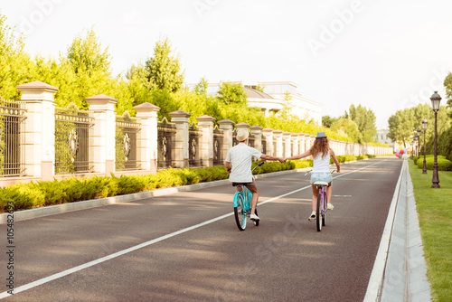 Photo of two lovers riding bicycle in the park and holding hands