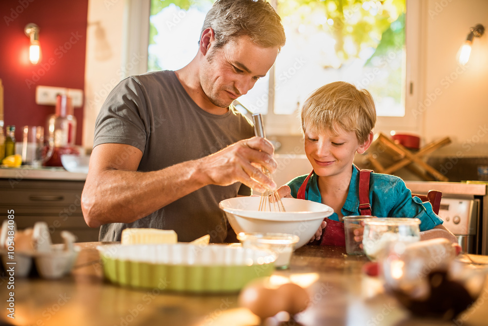 A eight years old blond boy is cooking with his dad