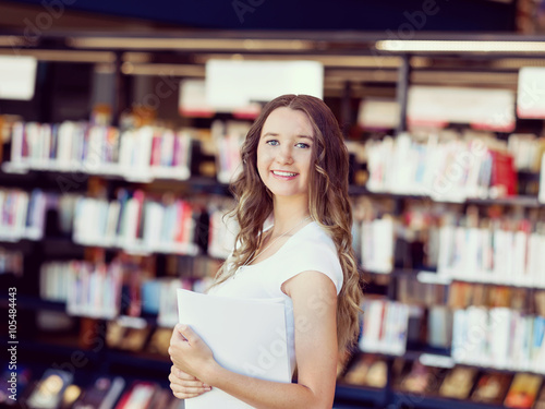 Happy female student holding books at the library