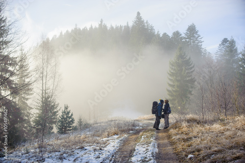 young couple of tourists staying in the winter woods on the road and kiss