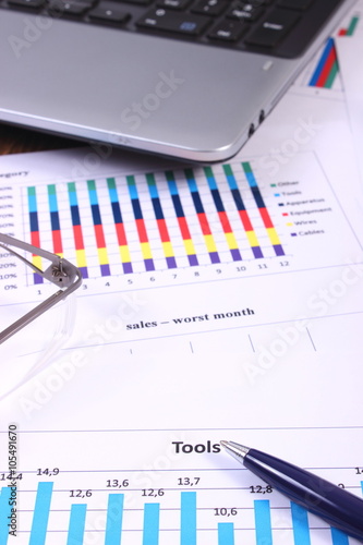 Pen, glasses and laptop on financial graph, business concept