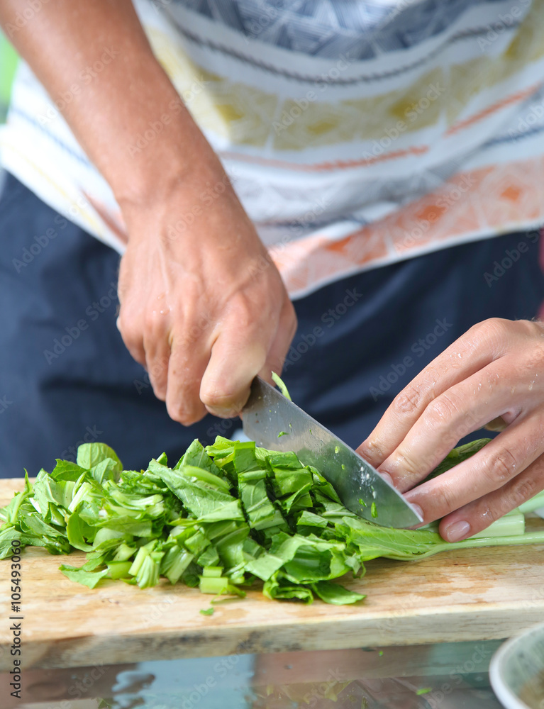 Man cutting green salad on the wooden board Man cutting green salad on the wooden board