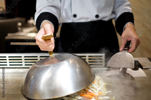 Fotografia Japanese chef deliberately preparing and cooking traditional beef teppanyaki on