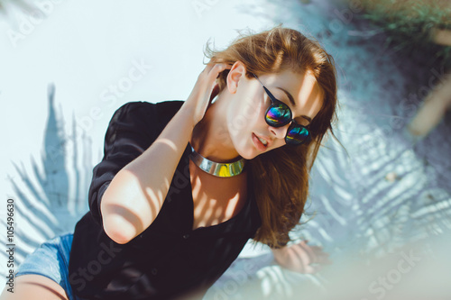 young beautiful girl in sunglasses denim shorts and shirt posing while lying on a hammock, beautiful woman, brunette resting on vacation at the beach, relax, outdoor portrait