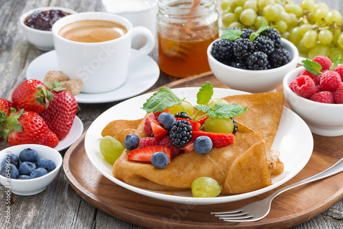 breakfast - crepes with fresh berries and honey, coffee, closeup