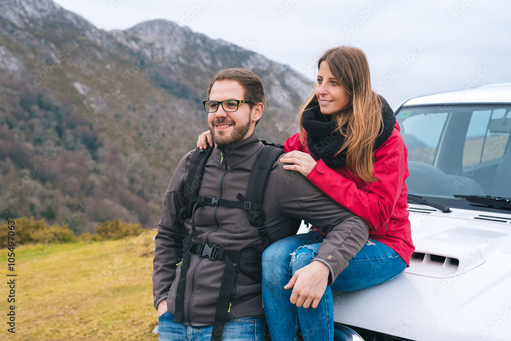 Young couple in love leaning on car, hiking outdoor on vacation, enjoying relaxing rural holidays.