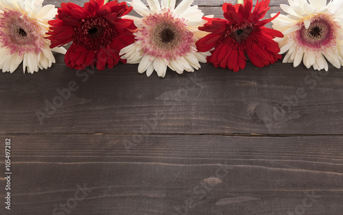 Pink and red gerbera flowers are in the wooden background