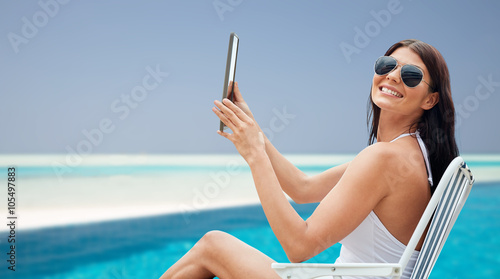 smiling woman with tablet pc sunbathing on beach