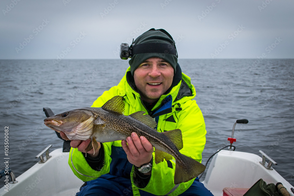 Happy angler with fresh caught cod fish Happy angler with fresh caught cod fish