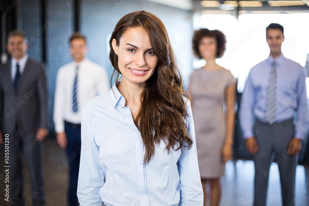 Businesswoman smiling at camera while his colleagues standing Businesswoman smiling at camera while his colleagues standing