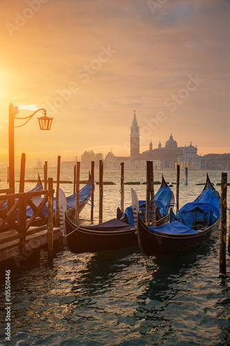 Gondolas by Saint Mark square during sunrise with San Giorgio di Maggiore church in the background in Venice Italy © nexusseven