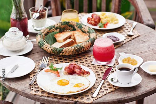 Perfrect healthy breakfast on patio in summer day. Fried eggs, cappuccino, fruits and muesli. Yummy and delicious