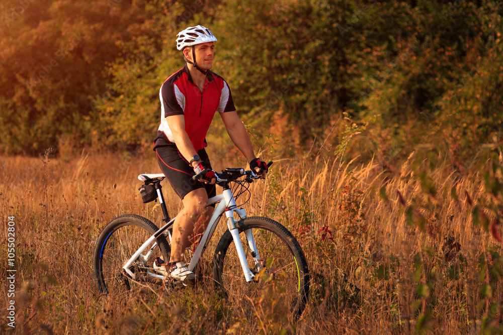 Man is riding a mountain bike in the field