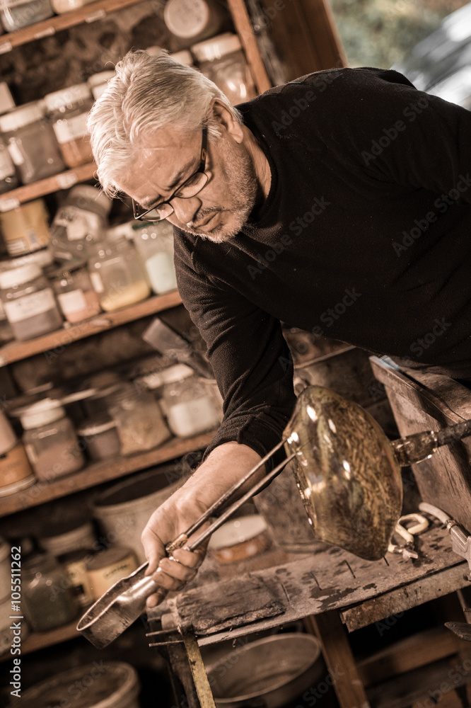 Glassblower forming molten glass in his worshop Glassblower forming molten glass in his worshop
