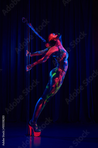 Female pole dancer in bright neon colours under ultraviolet (UV) light on background © Alex Shadrin