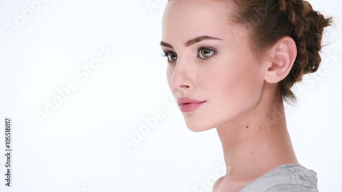 Peaceful beautiful woman without emotion looks away and  posing for the camera on white background