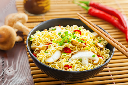 Bowl of instant noodles with shiitake mushrooms, pepper and onion on table, Asian food, top view