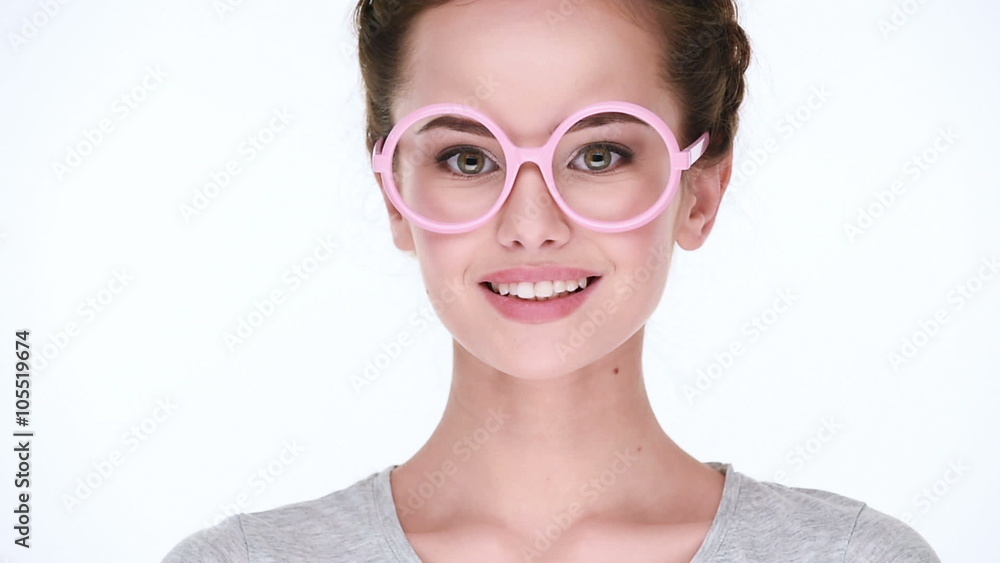 Young beautiful smiling woman in glasses pink color posing at camera on white background. Closeup view. Young beautiful smiling woman in glasses pink color posing at camera on white background. Closeup view.