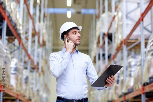 man with clipboard and smartphone at warehouse