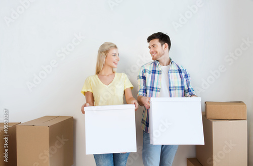 smiling couple with big boxes moving to new home