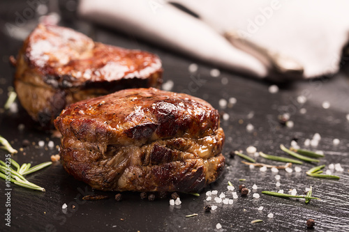 Grilled steak meat (mignon) on the dark surface photo