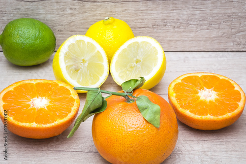several mature citrus on a wooden table - lemon, lime and tangerine 