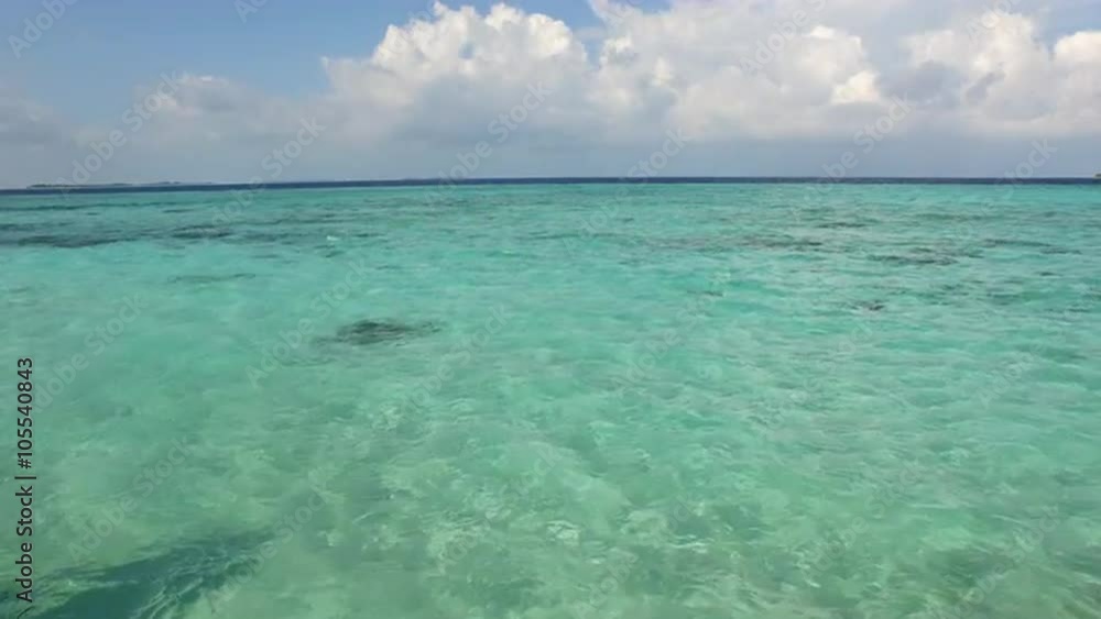 AERIAL: Young woman in bikini standing at the edge of the pool in ocean front villa pool and looking towards the sea horizon