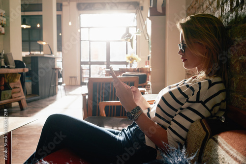 Photography Beautiful blonde girl working at a coffee shop with a smart-phone