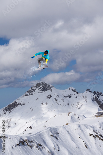 Snowboarder making jump, extreme mountain freeride.