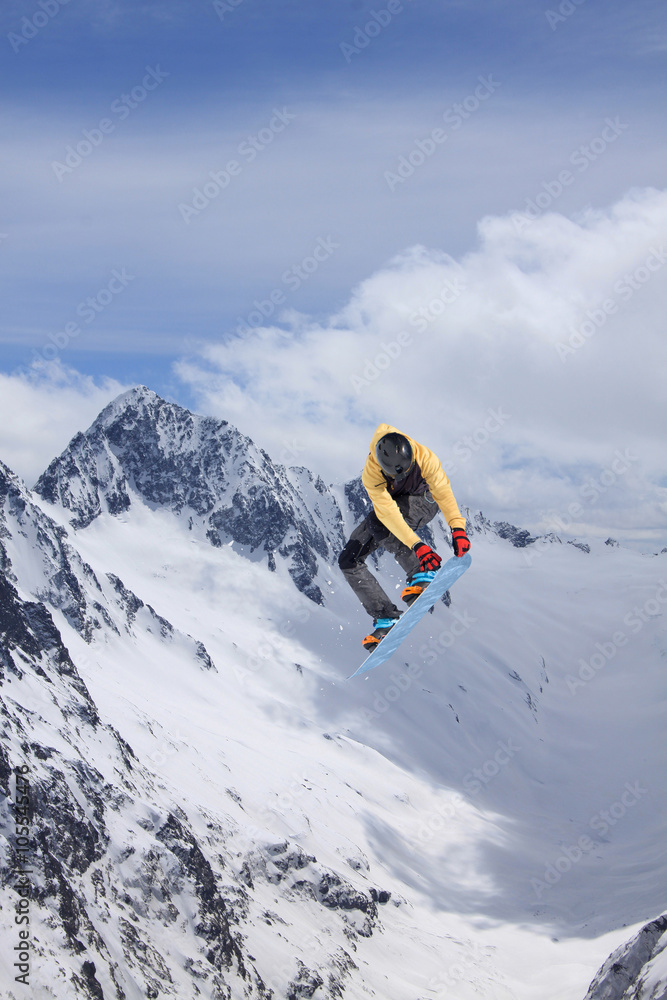 Snowboarder making jump, extreme mountain freeride.