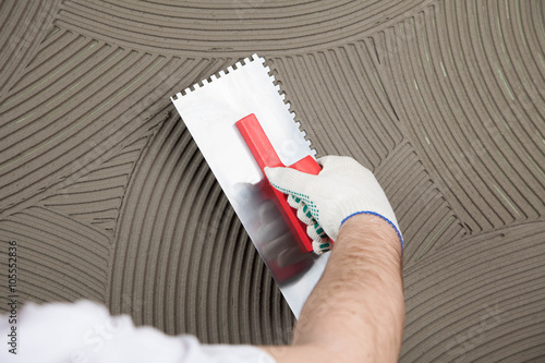 the worker applies glue for a tile on a wall