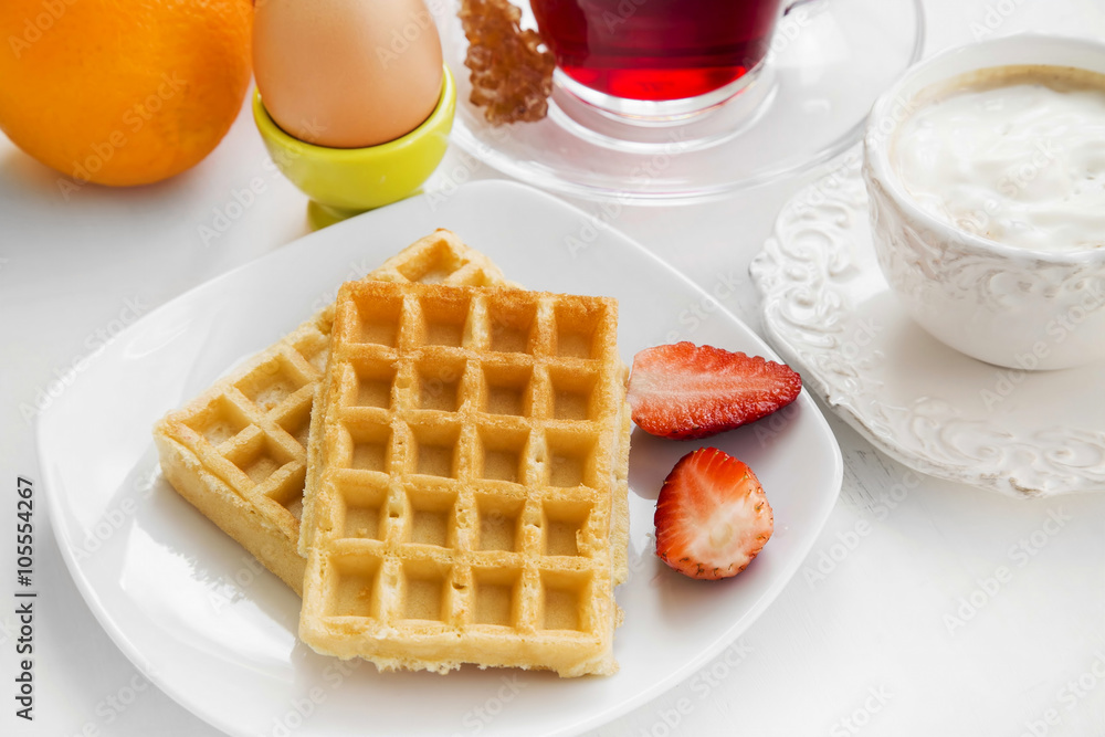 Breakfast meal with waffles and strawberries, fresh fruits , tea Breakfast meal with waffles and strawberries, fresh fruits , tea