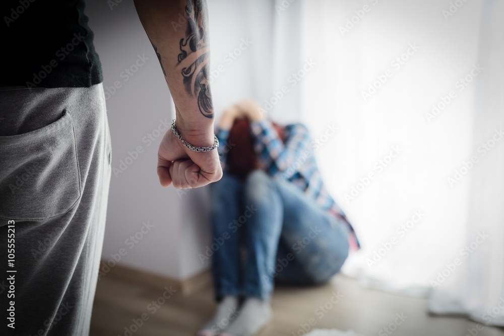 A young woman is sitting scared on the floor