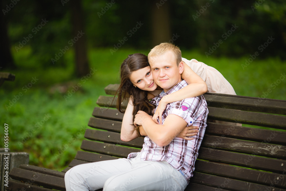 Attractive couple sitting on bench in the park Attractive couple sitting on bench in the park