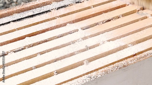 Brushing powdered sugar varroa treatment into bee spaces 