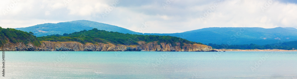 Rocks, mountains and sea. Rocky shore wooded mountains and the sea. Beautiful seascape. Panoramic shot.