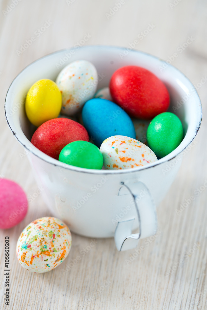 Fototapeta premium Easter candy eggs in miniature cup on wooden surface