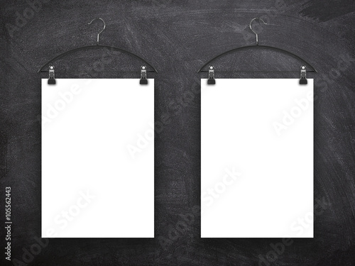 Close-up of two hanged blank frames with clothes hanger against blackboard background