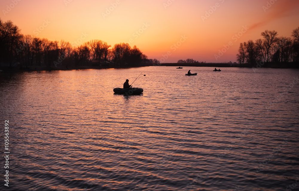 Beautiful landscape with orange sunrise, lake and fishermen 