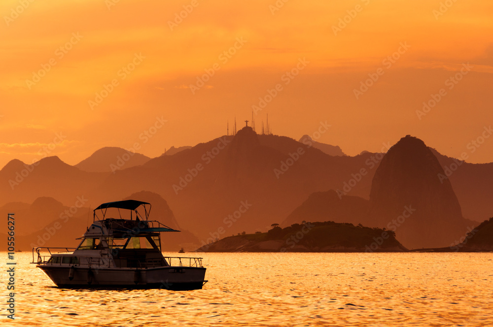 Lonely Boat in the Ocean by Sunset with Rio de Janeiro Mountains in the Horizon