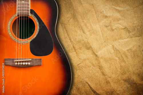 Acoustic guitar resting against a blank grunge background with c