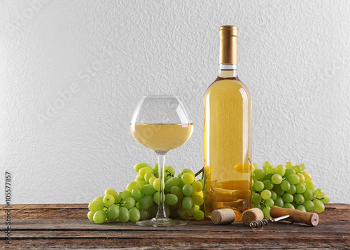 Wine and grape on wooden table against light background