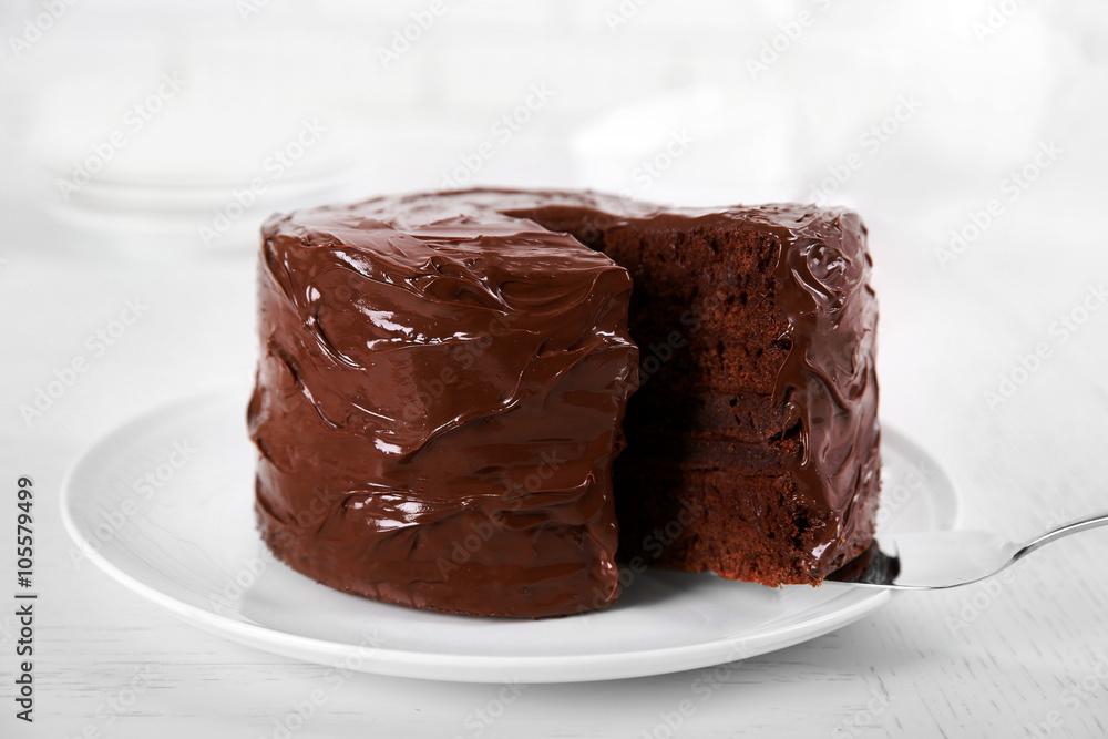 Chocolate cake on plate with a cut piece on unfocused background, closeup
