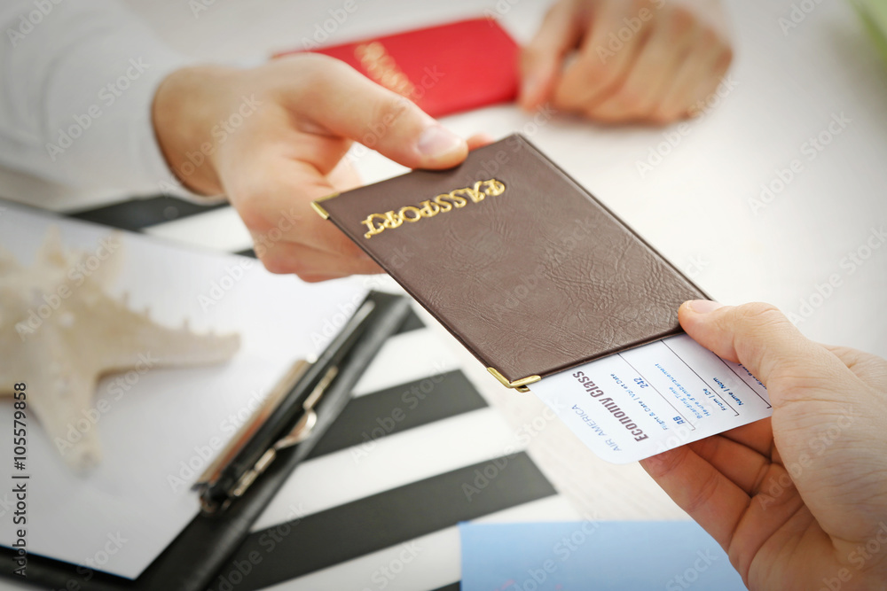 Agent giving passport and ticket to customer in the office of travel company Agent giving passport and ticket to customer in the office of travel company